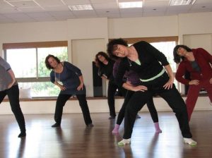 קבוצת נשים מתרגלת מתיחה צידית בסטודיו עם רצפת עץ
