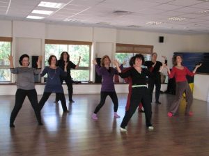קבוצת נשים עומדות בתנוחת צ'י קונג מול חלונות גדולים