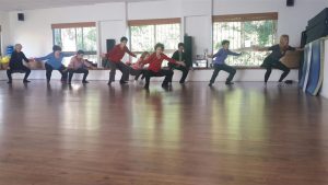 קבוצה בעמידת סוס עם ידיים פתוחות לצדדים בסטודיו