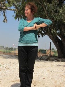 פנינה מתוק עומדת עם ידיים מוצלבות על החזה בשמש בחוץ