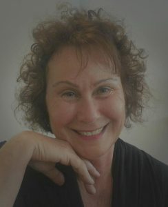 דיוקן מקרוב של פנינה מתוק מחייכת עם סנטר נשען על יד